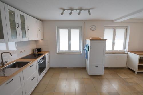 a kitchen with white cabinets and a refrigerator at Gästehaus Albero in Lindau