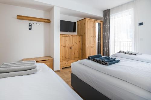 a bedroom with two beds and a tv on the wall at Piccola Cesa B&B in Canazei