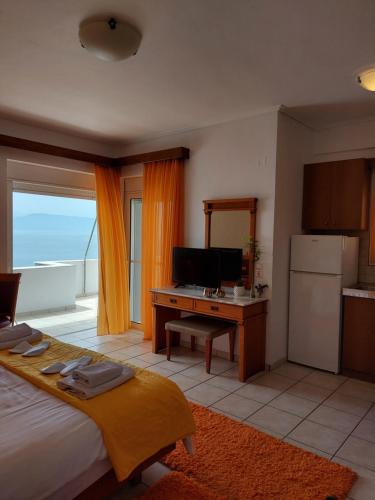 a bedroom with a bed and a desk and a kitchen at Anemolia Studios in Loutra Edipsou
