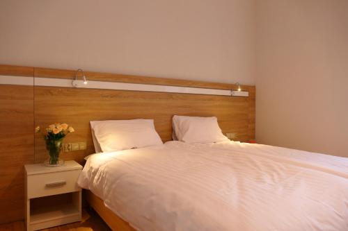 ein Schlafzimmer mit einem weißen Bett und einer Vase aus Blumen in der Unterkunft Sienkiewicza Centrum in Kielce