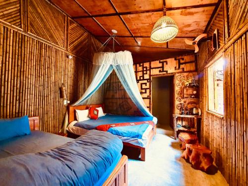 Un dormitorio con dos camas en una habitación con paredes de madera. en Little Yen's Homestay, en Mèo Vạc