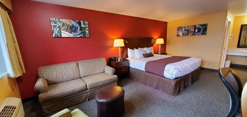 Olympic Inn & Suites في أبردين: غرفه فندقيه بسرير واريكه