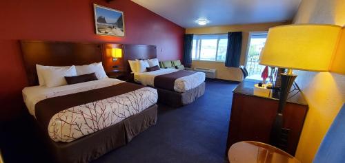 a hotel room with two beds and a lamp at Olympic Inn & Suites in Aberdeen