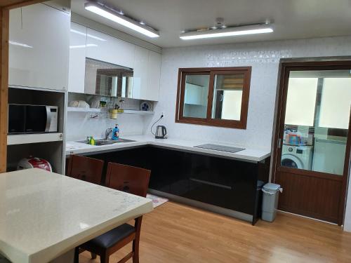 - une cuisine avec un évier et une table avec un comptoir dans l'établissement Oasis Pension, à Seogwipo
