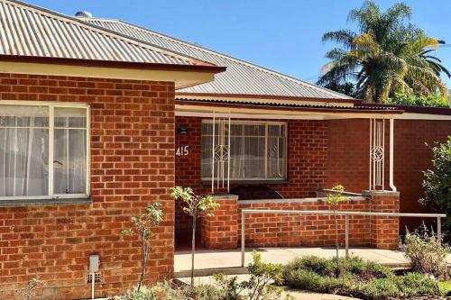a red brick house with a palm tree behind it at Young Olive in Albury