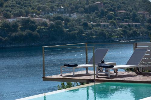 two chairs sitting on a dock next to a swimming pool at Villa Anthelia-Idyllic view and private access to the sea in Sivota