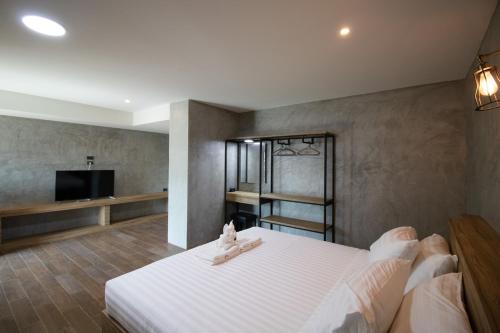 a bedroom with a white bed and a television at Rabbit Hotel Phimai in Pi Mai