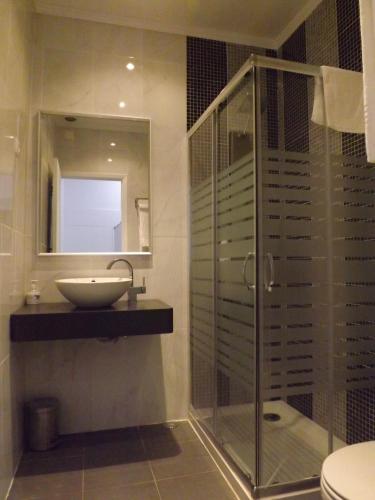 a bathroom with a glass shower and a sink at Residencial Valentina in Lisbon