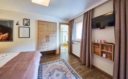 a bedroom with a bed and a tv and a window at Fuchs und Gretl in Saalbach-Hinterglemm