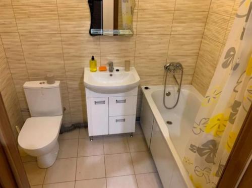 a bathroom with a toilet and a sink and a tub at Новострой Прокофьева in Sumy