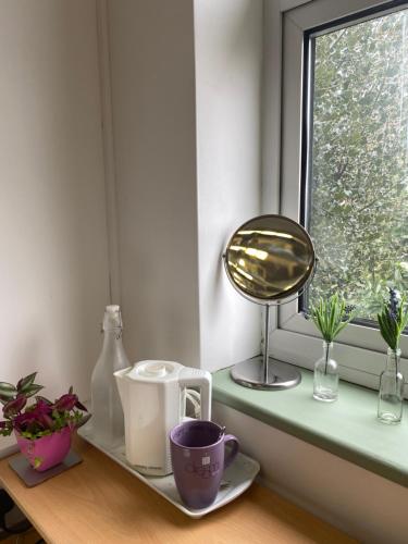 a window sill with a table with a cup and a mirror at Worcester Homestay in Worcester