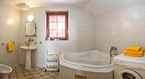 a bathroom with a tub and a sink and a washing machine at Drevenica Michael in Liptovský Trnovec