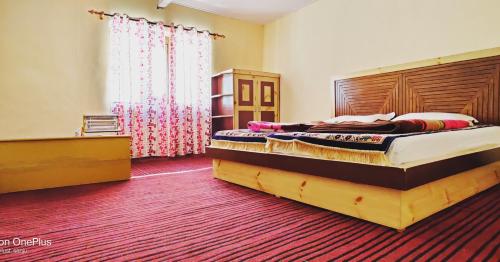 a bedroom with a large bed with a wooden headboard at Spiti Horizon Homestay in Kaza