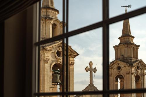 a window view of a church and a cross at 1926 Le Parisot Boutique Suites in Valletta