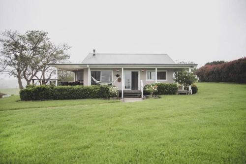 a small white house with a green lawn at Milton Woodstock Homestead Luxury retreat with NEW 11M POOL just minutes from the beach in Milton