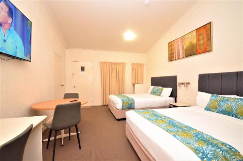 Habitación de hotel con 2 camas y mesa en Boulevarde Motor Inn, en Wagga Wagga