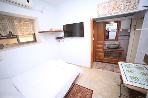 a bedroom with a bed and a television in a room at Ahuzat Shaul - Studio in H̱adera