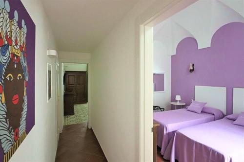 two beds in a room with purple walls at Casa Assuntina in Positano