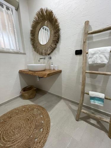 ein Bad mit einem Waschbecken und einem Wandspiegel in der Unterkunft Bay View Apartment in Porto Torres
