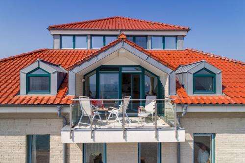 a house with an orange roof with chairs on the balcony at Turm-Appartement Strandburg in Fehmarn