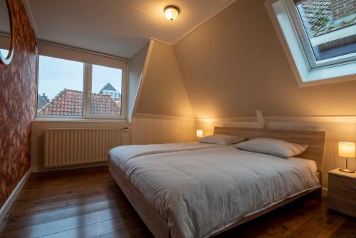 a bedroom with a large bed and two windows at Van Gogh Huis Medemblik in Medemblik