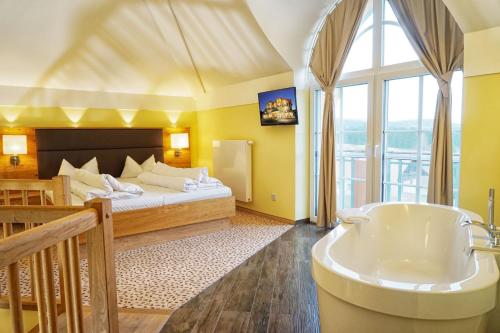 a hotel room with a tub and a bed at Das Stemp Wellnessresort 4 Sterne Superior in Büchlberg