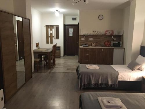 a room with two beds and a kitchen with a table at Aranykorona Apartmanház in Miskolc