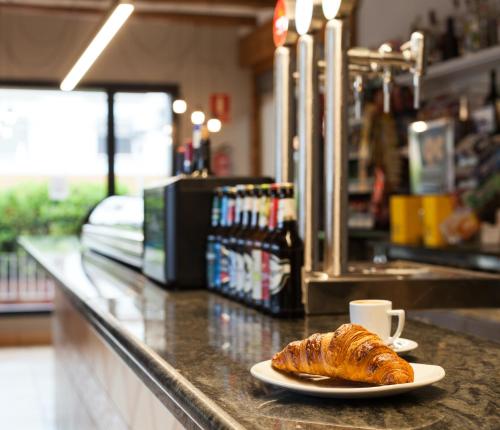 a plate of croissant on a counter with a cup of coffee at Hostal Restaurant Roma in Cubells