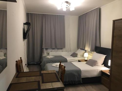 a hotel room with two beds and a table at Aranykorona Apartmanház in Miskolc