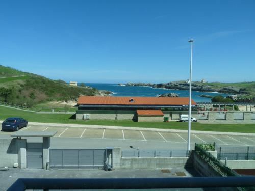 a building with a parking lot and a body of water at Apartamentos Maradentro in Soto de la Marina