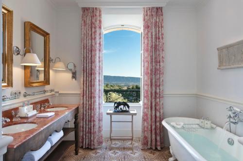 a bathroom with two sinks and a tub and a window at Airelles Gordes, La Bastide in Gordes