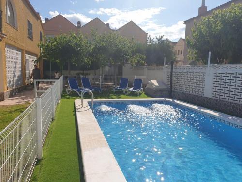 a swimming pool with blue chairs in a yard at Villa exclusiva cerca del mar con Piscina privada in Benicàssim