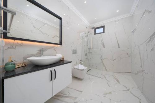 uma casa de banho branca com um lavatório e um chuveiro em Corleone - Modern Villa with Jacuzzi in Kalkan em Kas