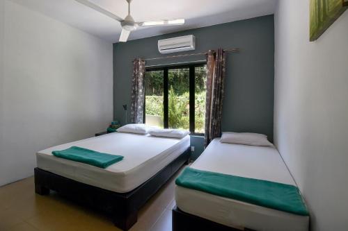 two beds in a room with a window at Green Peace Sungai Lembing in Sungai Lembing