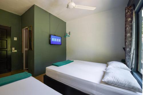 two beds in a room with a tv on the wall at Green Peace Sungai Lembing in Sungai Lembing