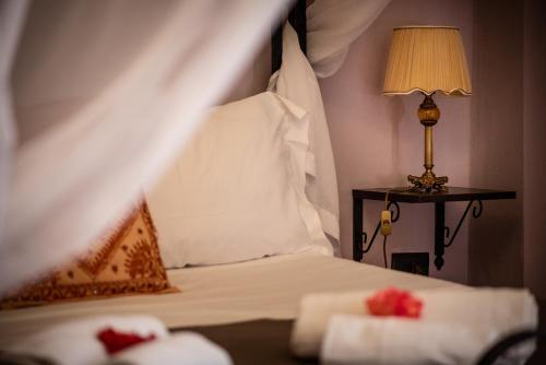 1 dormitorio con 1 cama con sábanas blancas y lámpara en SuiteSicily Rooms Palermo, en Altavilla Milicia