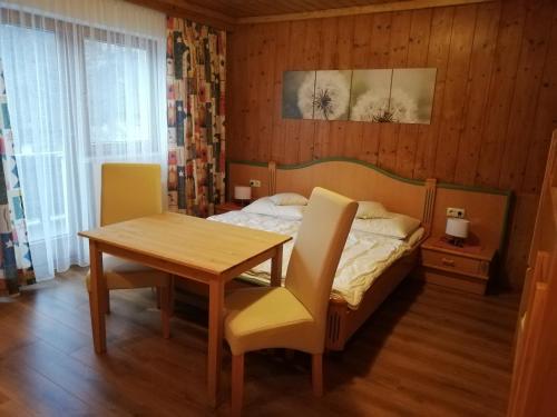 Schlafzimmer mit einem Bett, einem Tisch und Stühlen in der Unterkunft Haus Seppi in Neukirchen am Großvenediger