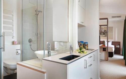 a white bathroom with a sink and a toilet at Best Motel in Vilsbiburg