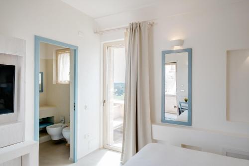 Habitación blanca con espejo y baño. en Masseria Cuturi, en Manduria