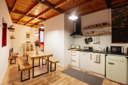 a kitchen with white cabinets and a wooden table at Casa Gaveto in Sabugal