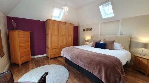 ピトロッホリーにあるWillows Cottageのベッドルーム1室(ベッド2台、ドレッサー、紫の壁付)