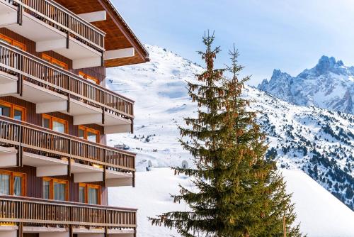 a christmas tree in the snow next to a building at Hotel Les Arolles in Méribel