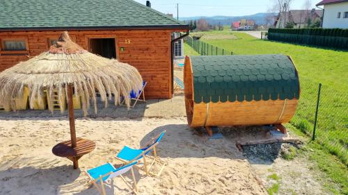 a small hut with chairs and a table and an umbrella at Apartamenty przy Jeziorze Żywieckim z widokiem na Skrzyczne in Żywiec
