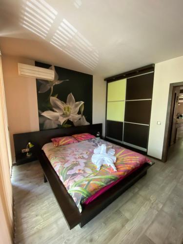 a bedroom with a large bed with a painting on the wall at Апартамент Мегилукс in Blagoevgrad