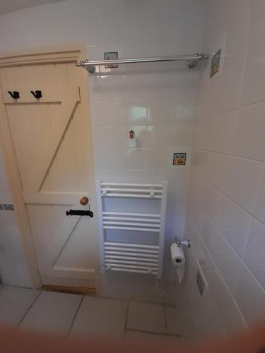 a white bathroom with a toilet and a toilet paper dispenser at Blue Skies in St Ives