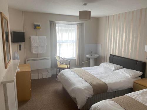 a hotel room with two beds and a desk at The White Hart Hotel in Holsworthy