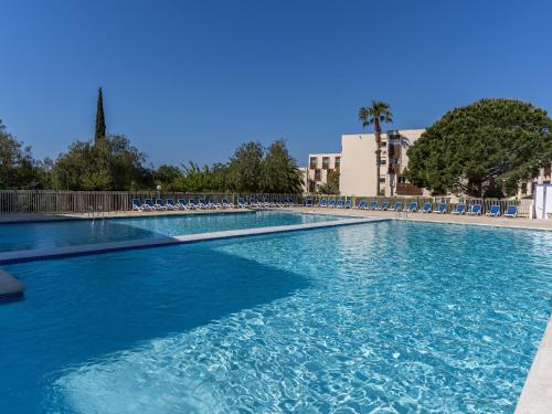 une grande piscine avec des chaises et de l'eau bleue dans l'établissement Vacancéole - Résidence L'Ile d'Or, à La Londe-les-Maures
