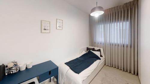 Luxury 3&4 Bedroom new apartments - close to the Beach & Bahai Gardens في حيفا: غرفة صغيرة بها سرير وطاولة زرقاء