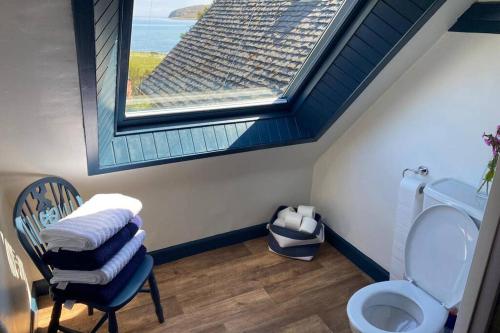a bathroom with a window and a toilet with a chair at Lamlash- Self catering accommodation with seaviews in Lamlash