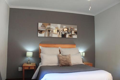 a bedroom with a bed with two night stands and two lamps at Nelspruit Lodge in Nelspruit